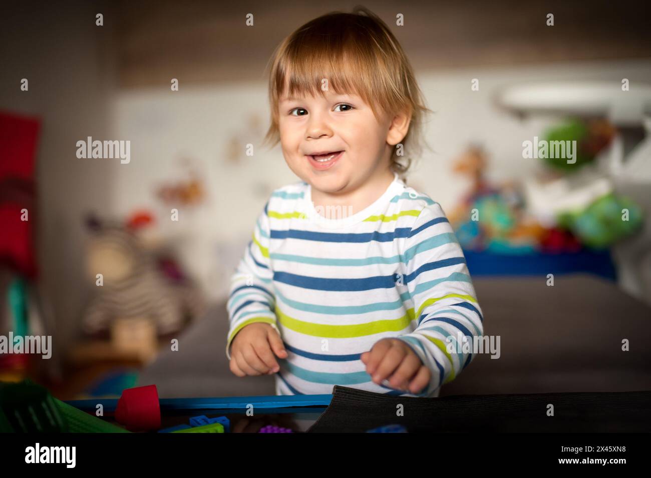 Niedlicher Junge, der mit seinen bunten Spielzeugen im Wohnzimmer spielt. Bildungsspielzeug, Kinderentwicklung Stockfoto