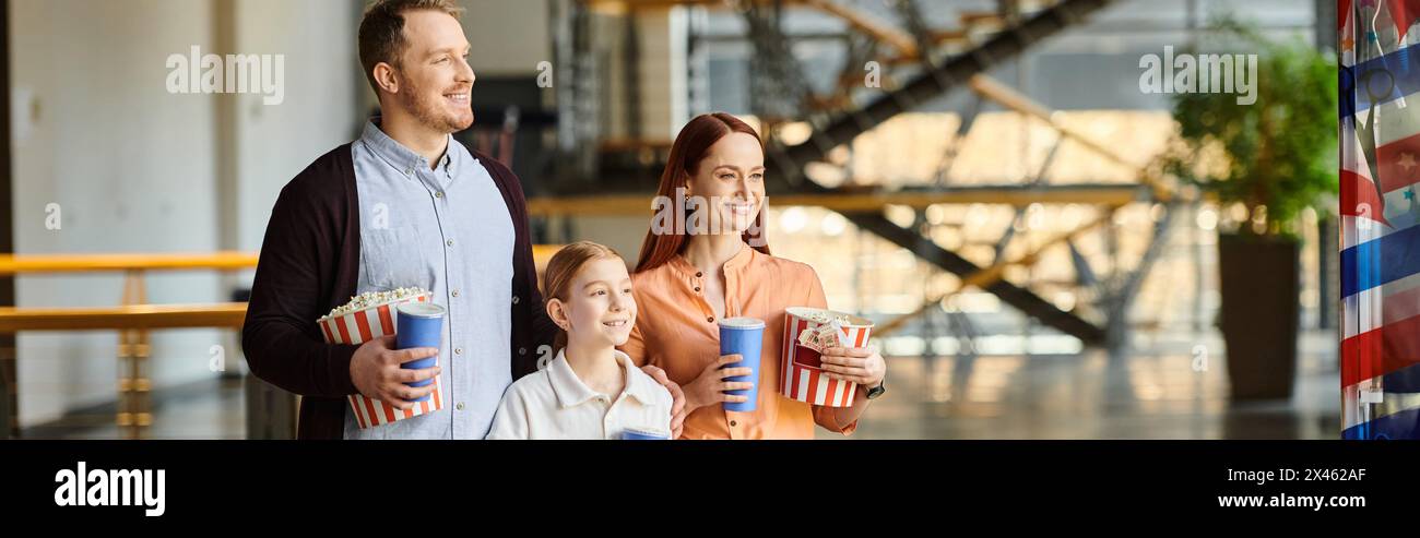 Ein Mann, eine Frau und ein Kind halten glücklich Popcorn, während sie einen Film im Kino sehen. Stockfoto