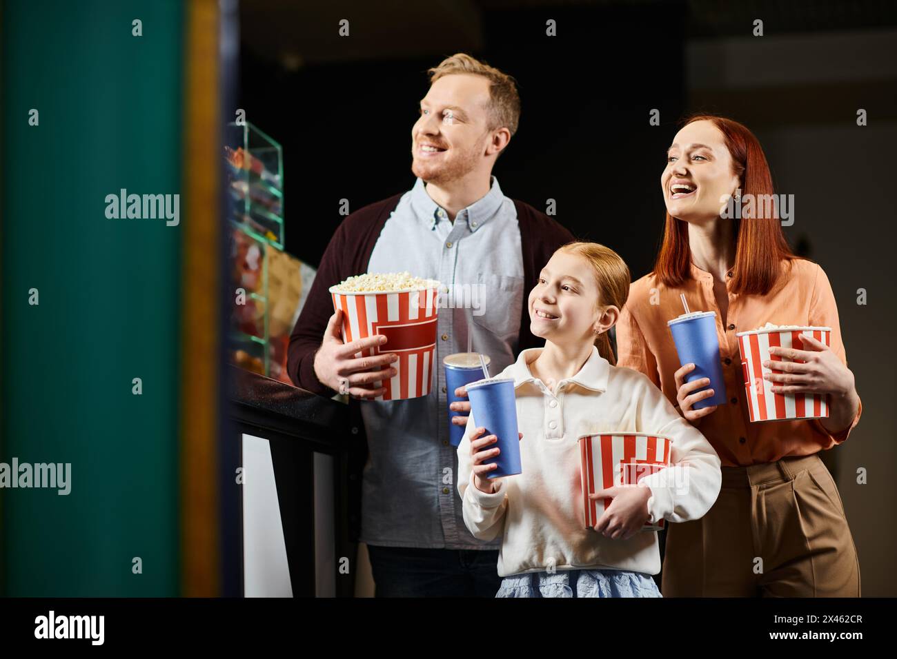 Eine glückliche Familie steht eng zusammen und genießt ein Kinoerlebnis mit Lächeln und Lachen. Stockfoto