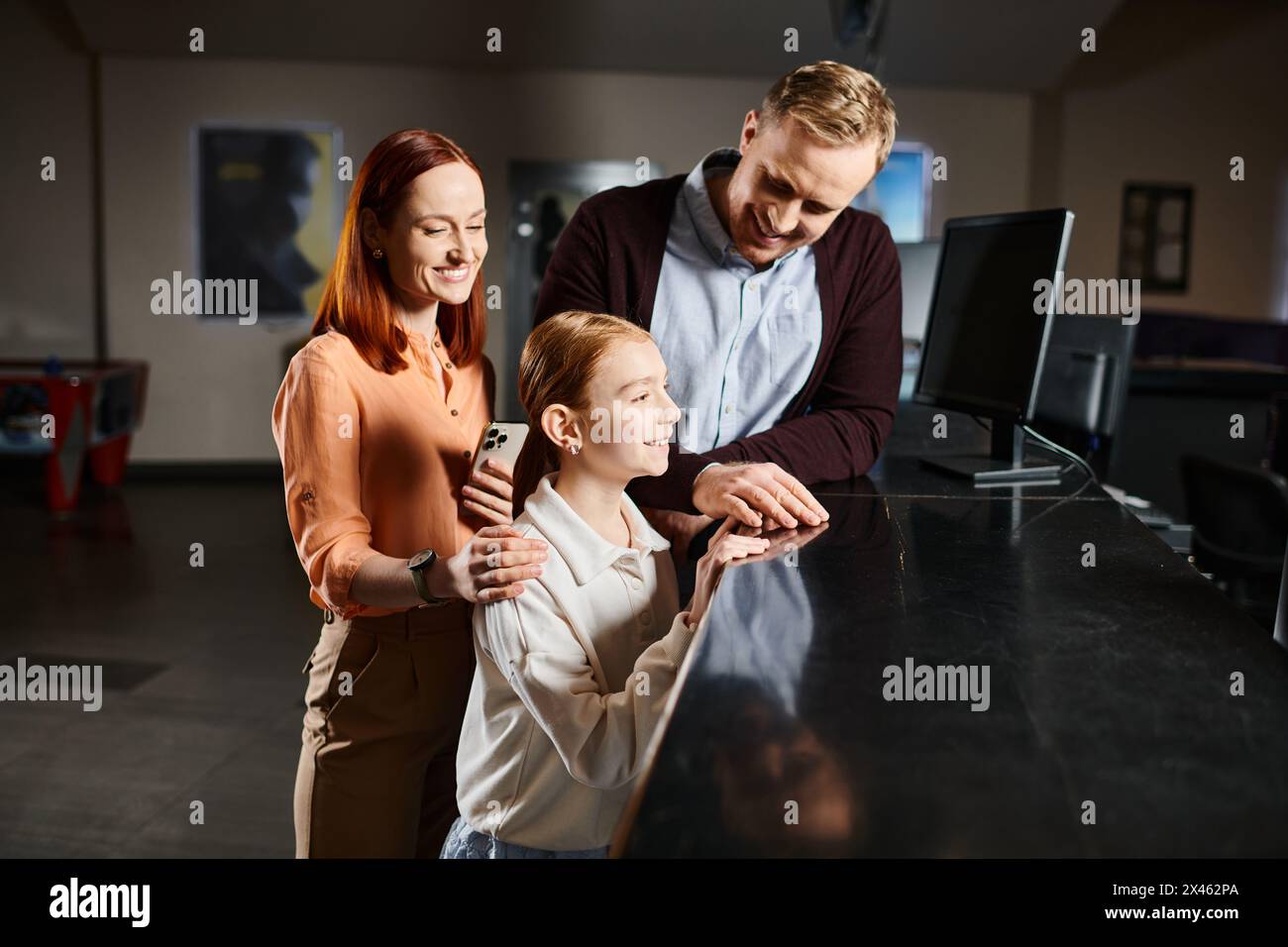 Ein Mann, eine Frau und ein Kind stehen zusammen, lächeln und genießen einen Filmausflug als glückliche Familie. Stockfoto