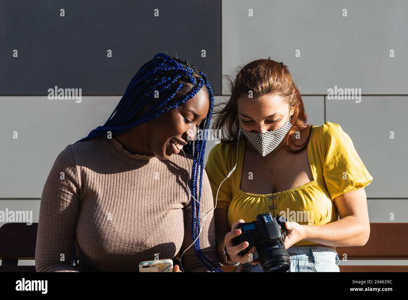 Begeisterte diverse Freundinnen, die Musik hören und durchschauen Fotos auf Fotokamera auf der Straße gemacht Stockfoto