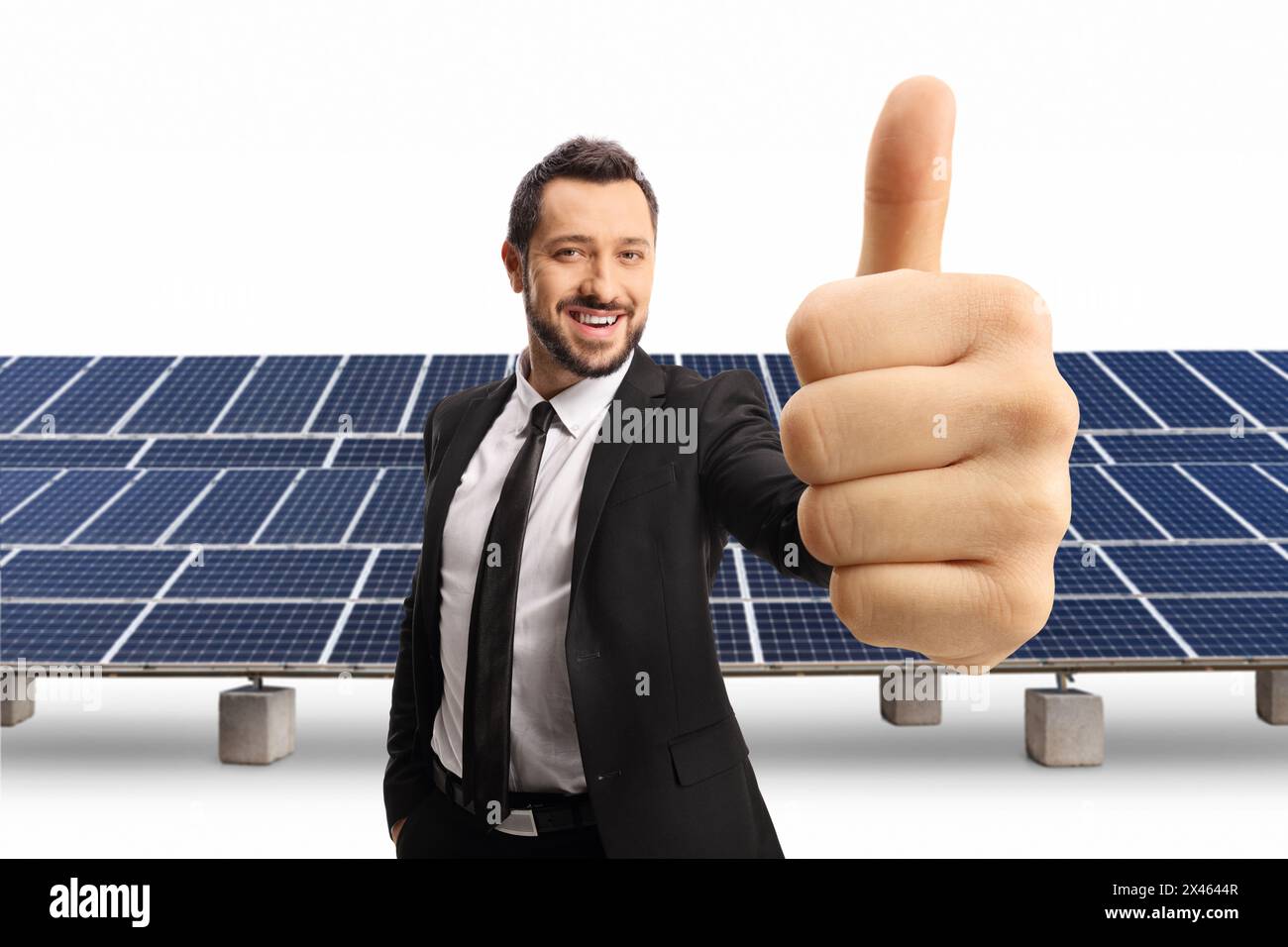 Glücklicher Geschäftsmann, der ein Daumen hoch Zeichen vor dem Solarfeld auf weißem Hintergrund zeigt Stockfoto