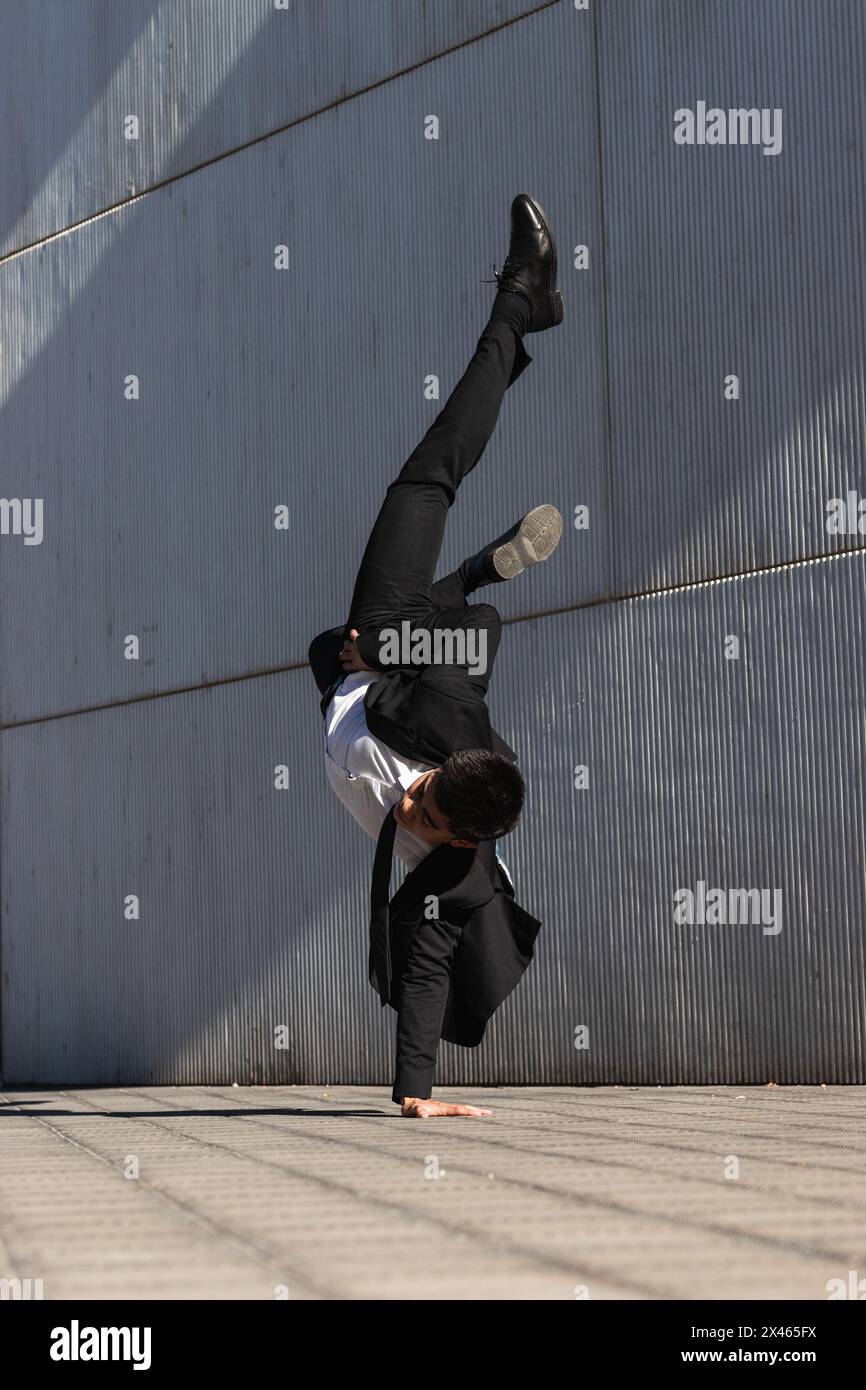 Asiatische männliche Unternehmer in formellen Anzug zeigt Breakdance Bewegung und Balancieren auf Arm im Handstand auf der Stadtstraße beim Schauen Bei der Kamera Stockfoto