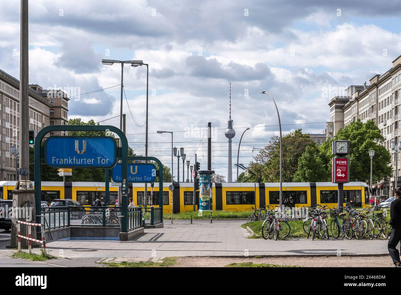 Blick auf die Karl Mark Allee vom Frankfurter Tor aus mit einer gelben Straßenbahn, die vorbeifährt und den Fernsehturm sichtbar in der Ferne, Berlin, Deutschland, EU Stockfoto