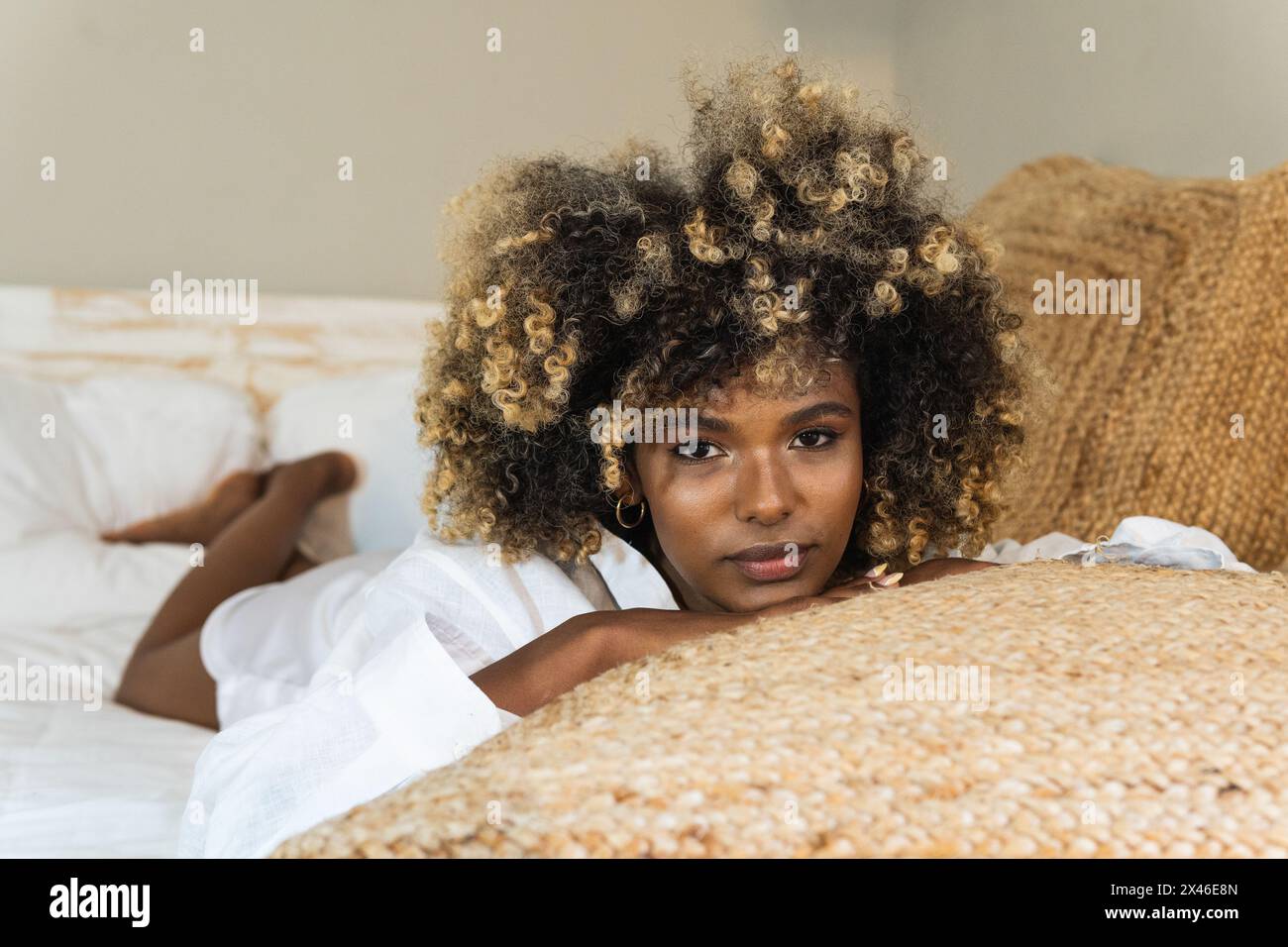 Attraktive afroamerikanische Frau, die sich auf dem Bett niederlegt und die Kamera anschaut Stockfoto