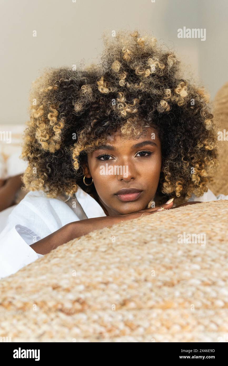 Attraktive afroamerikanische Frau, die sich auf dem Bett niederlegt und die Kamera anschaut Stockfoto