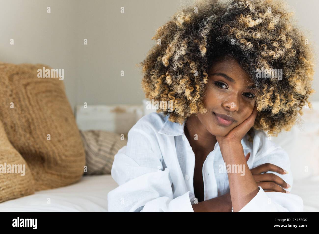 Attraktive afroamerikanische Frau, die sich auf dem Bett niederlegt und die Kamera anschaut Stockfoto