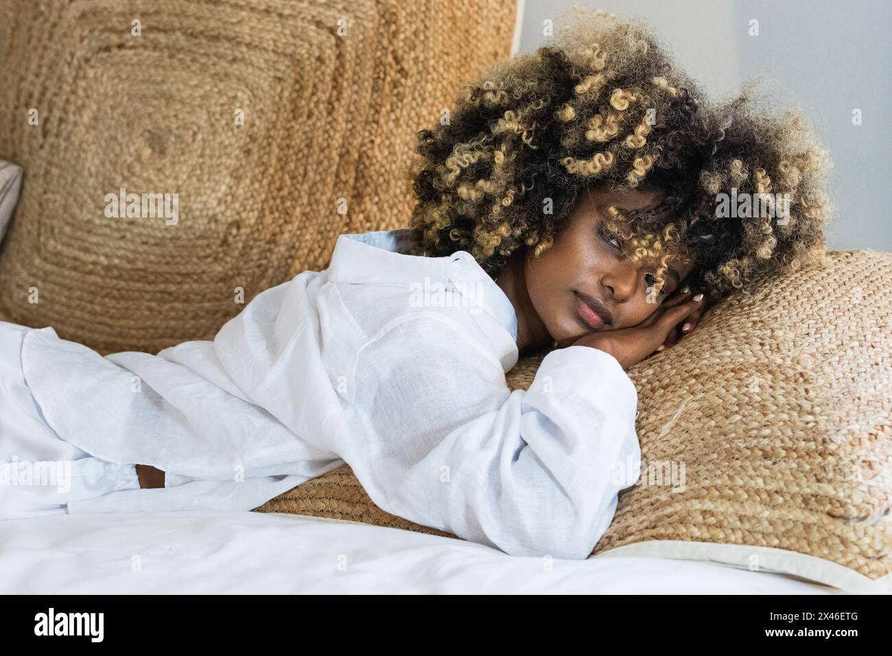 Attraktive afroamerikanische Frau, die sich auf dem Bett niederlegt und die Kamera anschaut Stockfoto