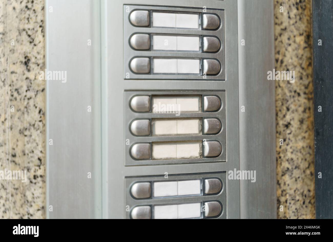 Eine detaillierte Ansicht eines an einer Wand angebrachten Sprechanlagen mit Tasten und einem Lautsprecher. Stockfoto