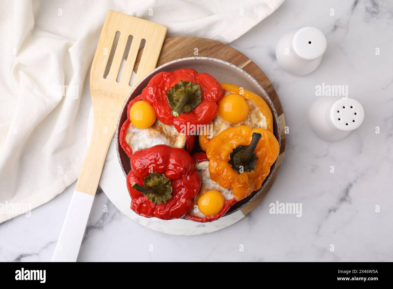 Köstliche gefüllte Paprika mit Spiegeleiern und Spatel auf weißem Marmortisch, Blick von oben Stockfoto