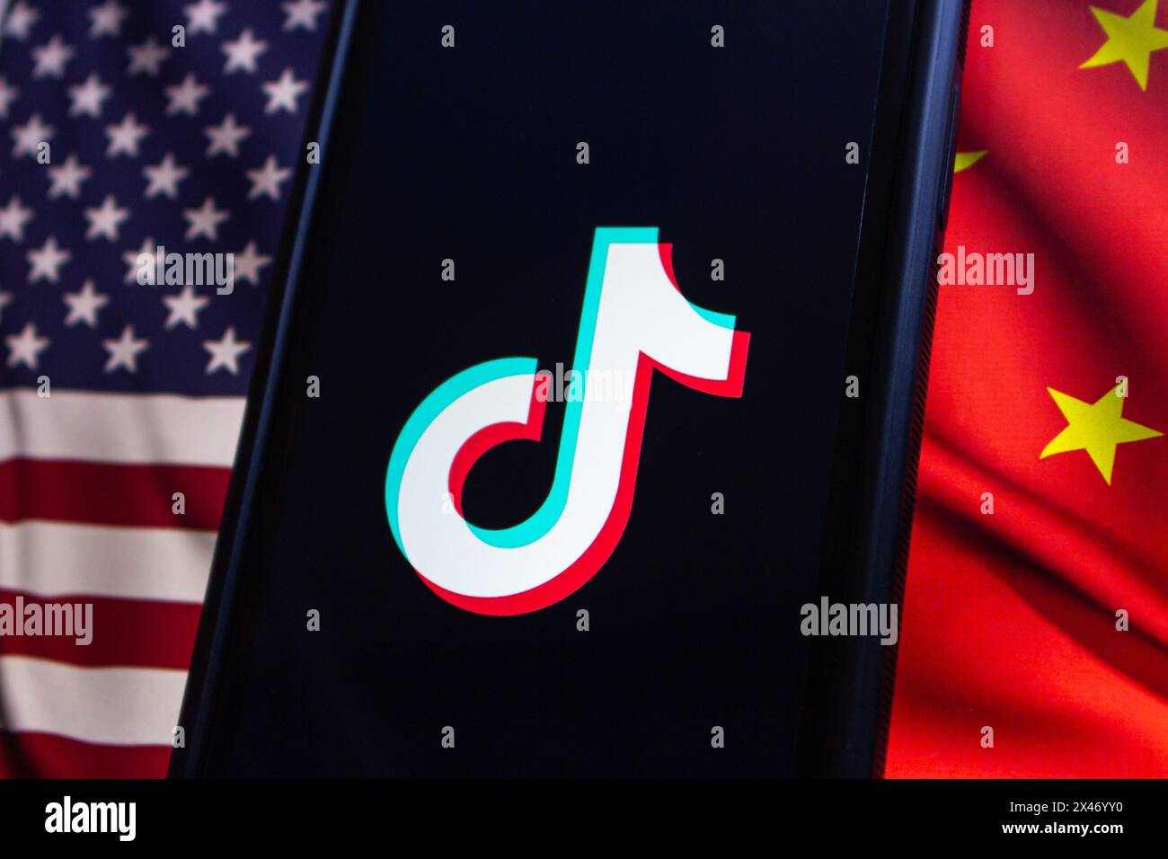 Vancouver, KANADA - April 30 2024 : TikTok-Logo auf einem iPhone-Bildschirm auf amerikanischer Flagge und chinesischer Flagge Stockfoto