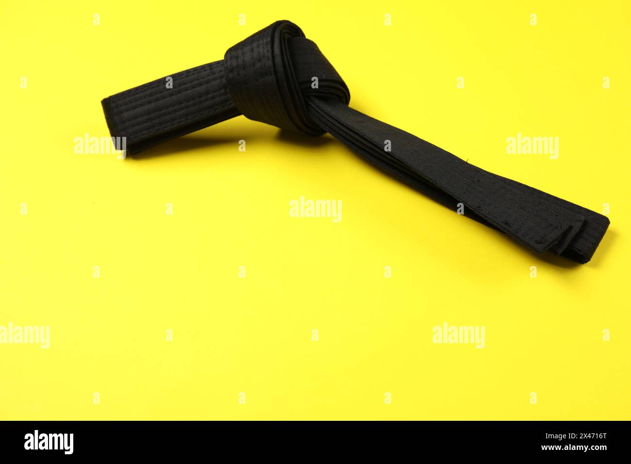 Schwarzer Karate-Gürtel auf gelbem Hintergrund, Platz für Text Stockfoto