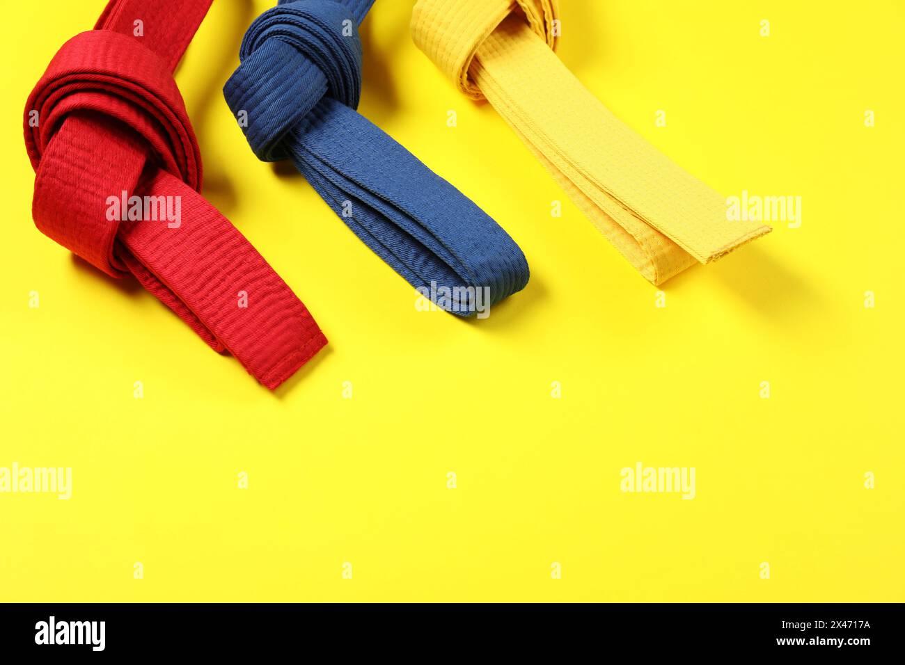 Bunte Karate-Gürtel auf gelbem Hintergrund, Platz für Text Stockfoto
