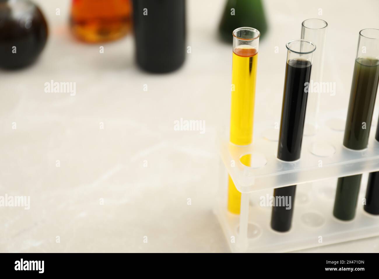 Reagenzgläser mit verschiedenen Rohölsorten auf hellem Marmortisch, Platz für Text Stockfoto