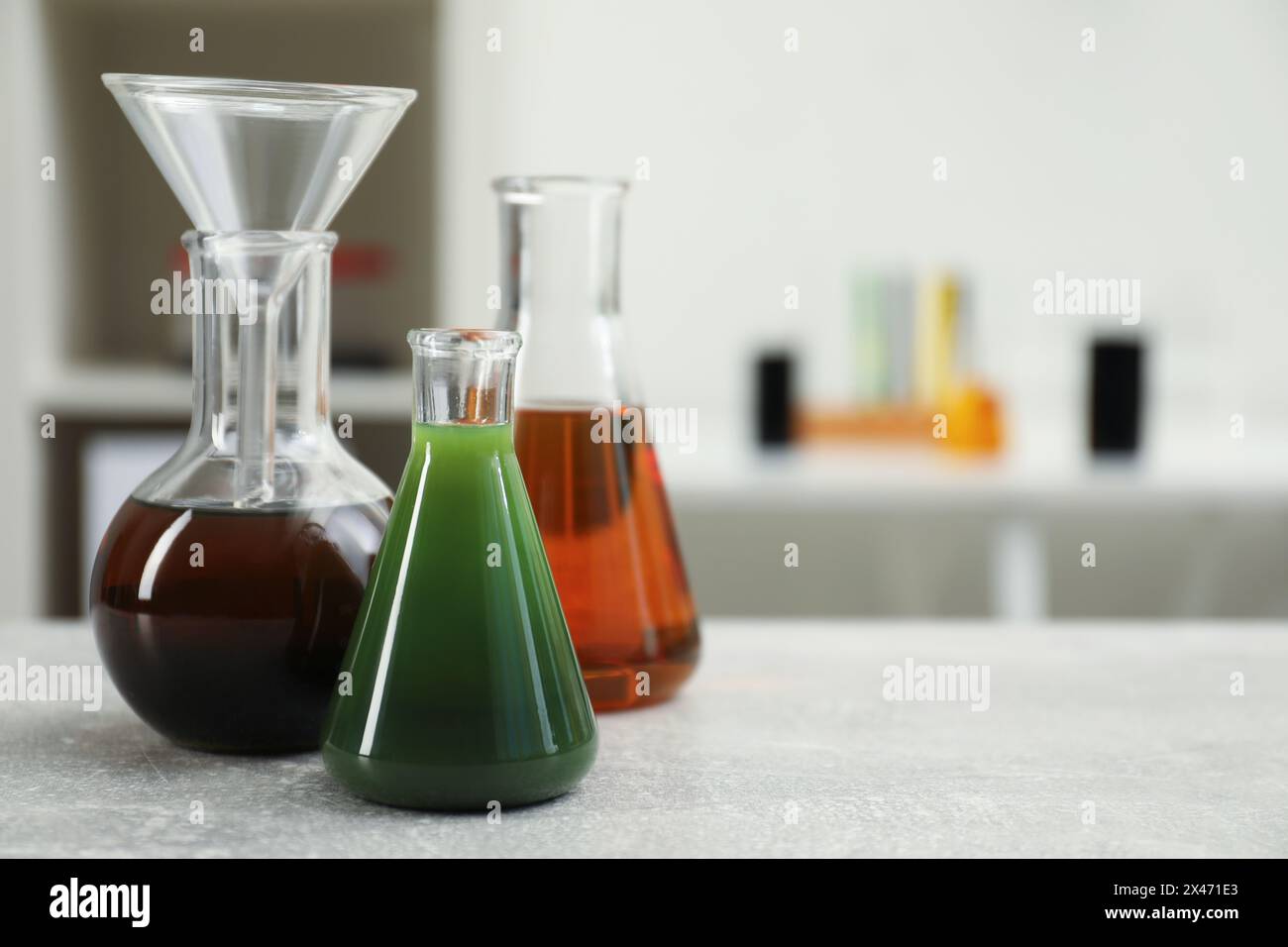 Laborglas mit verschiedenen Rohölsorten auf hellgrauem Tisch, Platz für Text Stockfoto