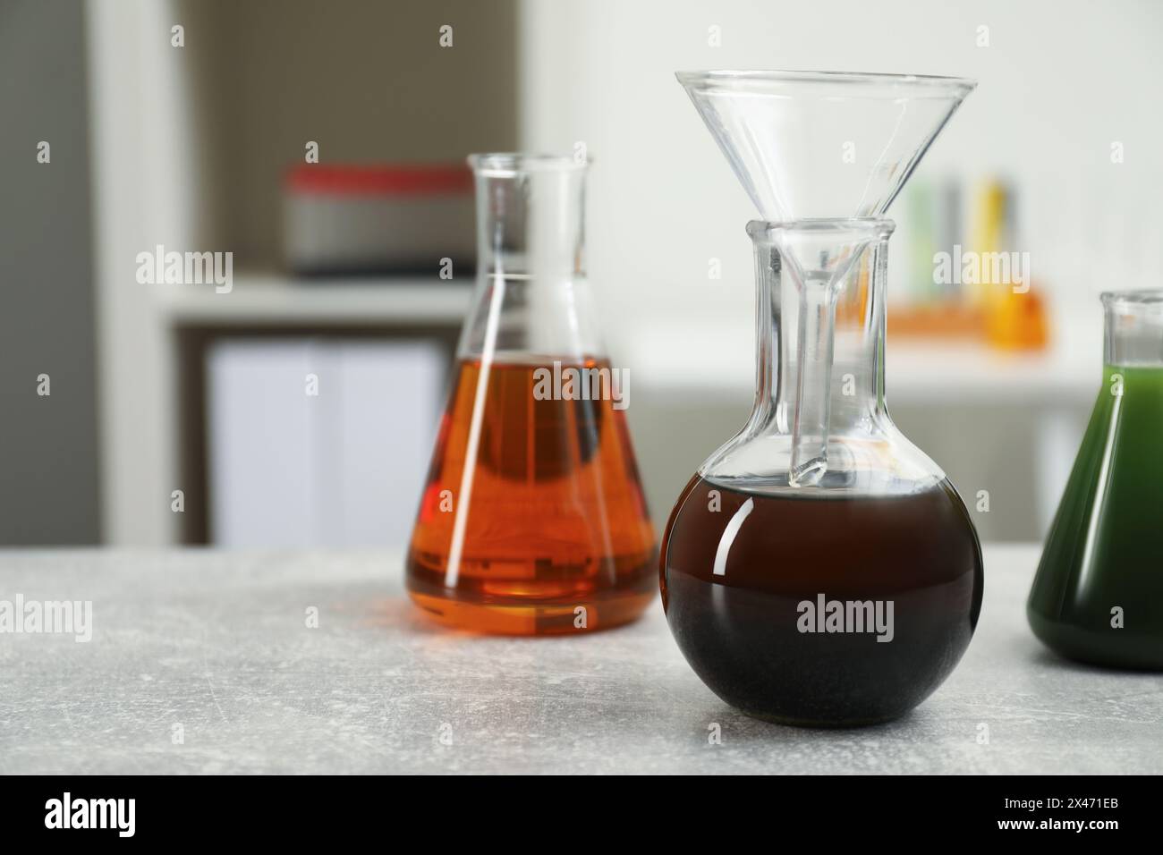 Laborglas mit verschiedenen Rohölsorten auf hellgrauem Tisch, Platz für Text Stockfoto