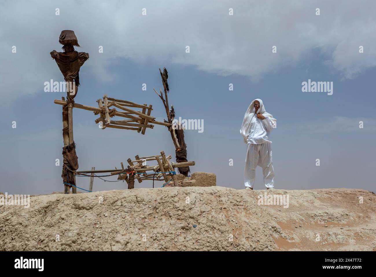Ein marokkanischer Mann steht neben einem Brunnen, aus dem Wasser aus einem Khettara im Tafilalet-Becken bei Rissani in Marokko gefördert wurde. Stockfoto