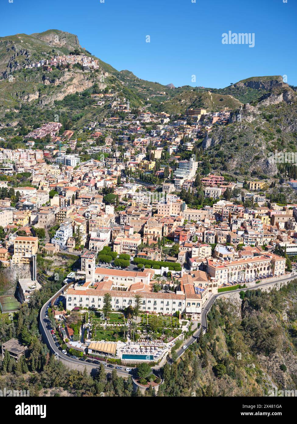LUFTAUFNAHME. Die touristische Stadt Taormina und oben links das Dorf Castelmola auf einem Hügel. Metropolitanstadt Mesina, Sizilien, Italien. Stockfoto