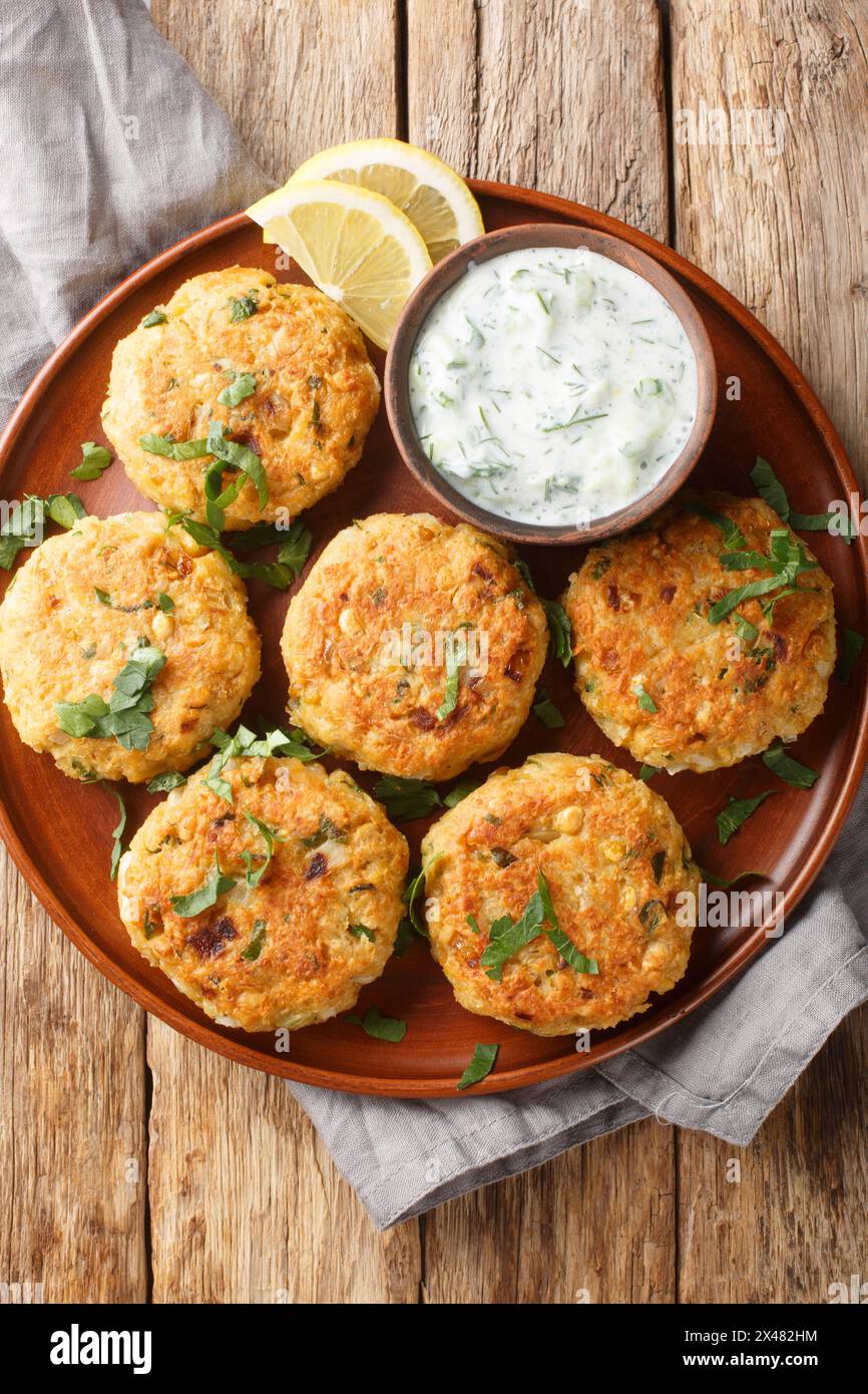 Kichererbsenfritter mit Tzatziki-Sauce in Nahaufnahme auf einem Teller auf einem Holztisch. Vertikale Draufsicht von oben Stockfoto