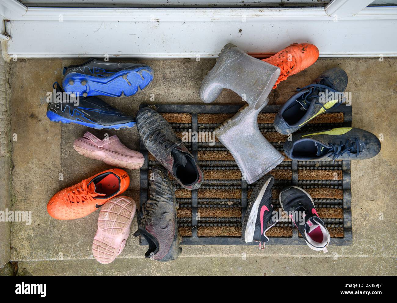 Eine Auswahl an Kinderschuhen liegt auf einer vorderen Türstufe. Stockfoto