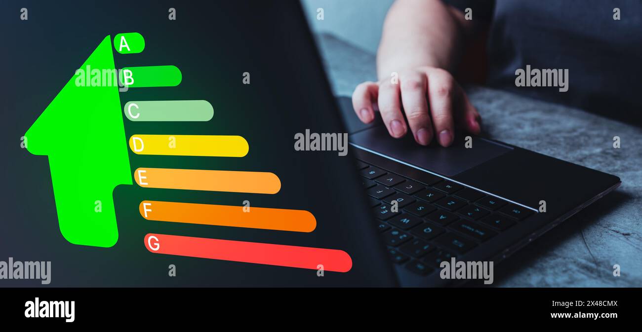 Frau, die einen Laptop für die Hauseffizienzklasse benutzt. Das Konzept des ökologischen und bioenergetischen Hauses. Energieklasse. Stockfoto