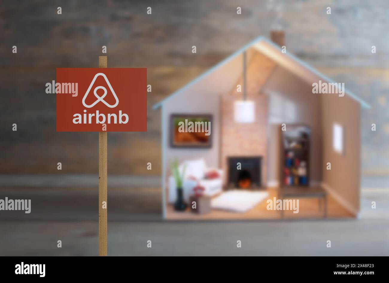 Airbnb-Schild neben einem Modellhaus mit Lichtern im Inneren Stockfoto