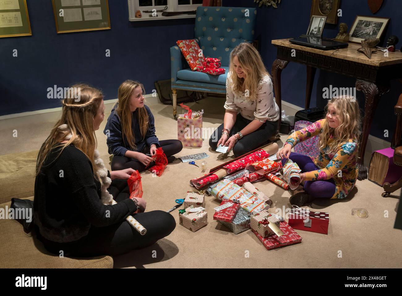 Mutter und Töchter verpacken Geschenke im Haus der Familie Dorset in Christmas, England, Großbritannien Stockfoto