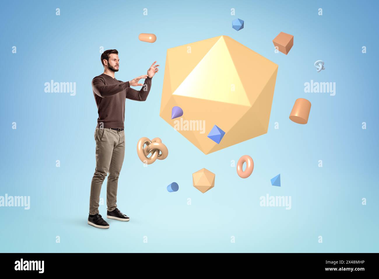 Junger Mann, der steht und versucht, geometrische Objekte zu manipulieren Stockfoto