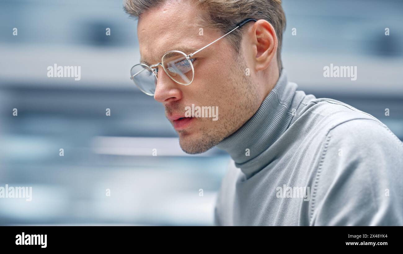 Modernes Büro Close-up Porträt: Schöner Geschäftsmann, der an seinem Schreibtisch sitzt und am Computer arbeitet. Professioneller Digitaler Unternehmer Lächelnd. Unscharfer Bewegungshintergrund. Stockfoto