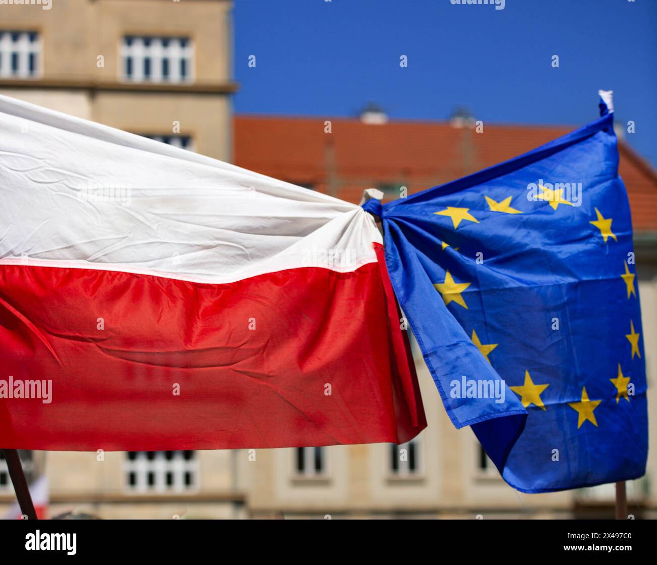 Nationalflagge Polens mit EU-Flagge im Stadtzentrum gegen Gebäude und blauen Himmel gebunden Stockfoto