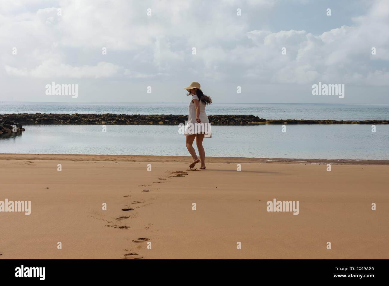 Frau mit Hut tanzt an einem paradiesischen Strand. dng Stockfoto