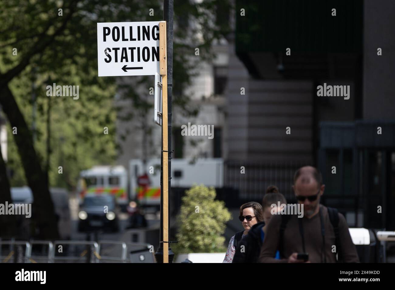 Die Menschen gehen an einem Schild vorbei, das auf eine Wahlstation vor den morgigen Kommunalwahlen in Westminster, London, zeigt. Morgen werden Kommunalwahlen in verschiedenen Teilen des Vereinigten Königreichs stattfinden, in denen die regierende Konservative Partei voraussichtlich zahlreiche Verluste erleiden wird. Stockfoto