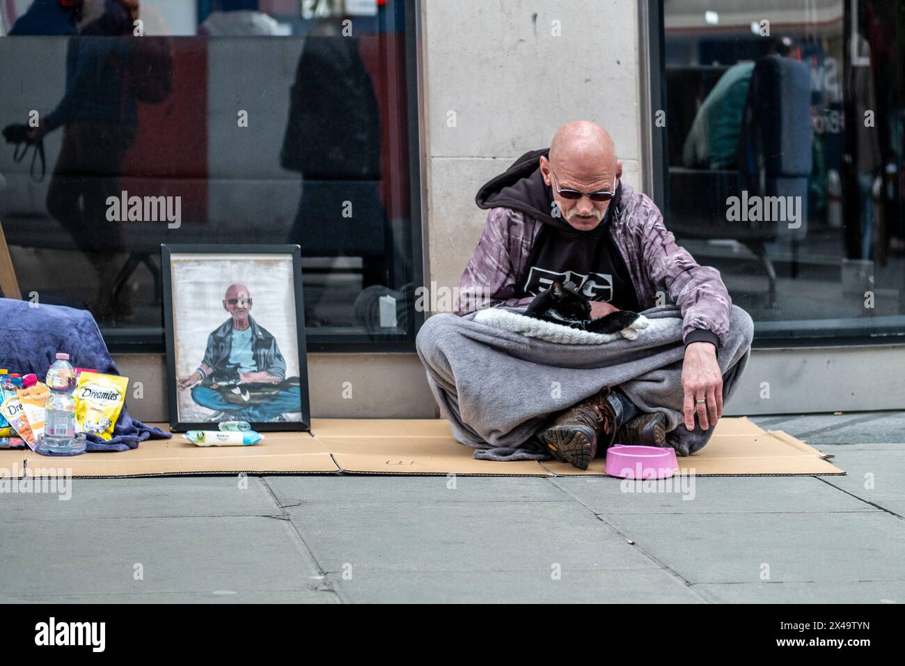 LONDON, 4. APRIL 2024: Ein Obdachloser mit einer Katze in der Oxford Street im West End Stockfoto
