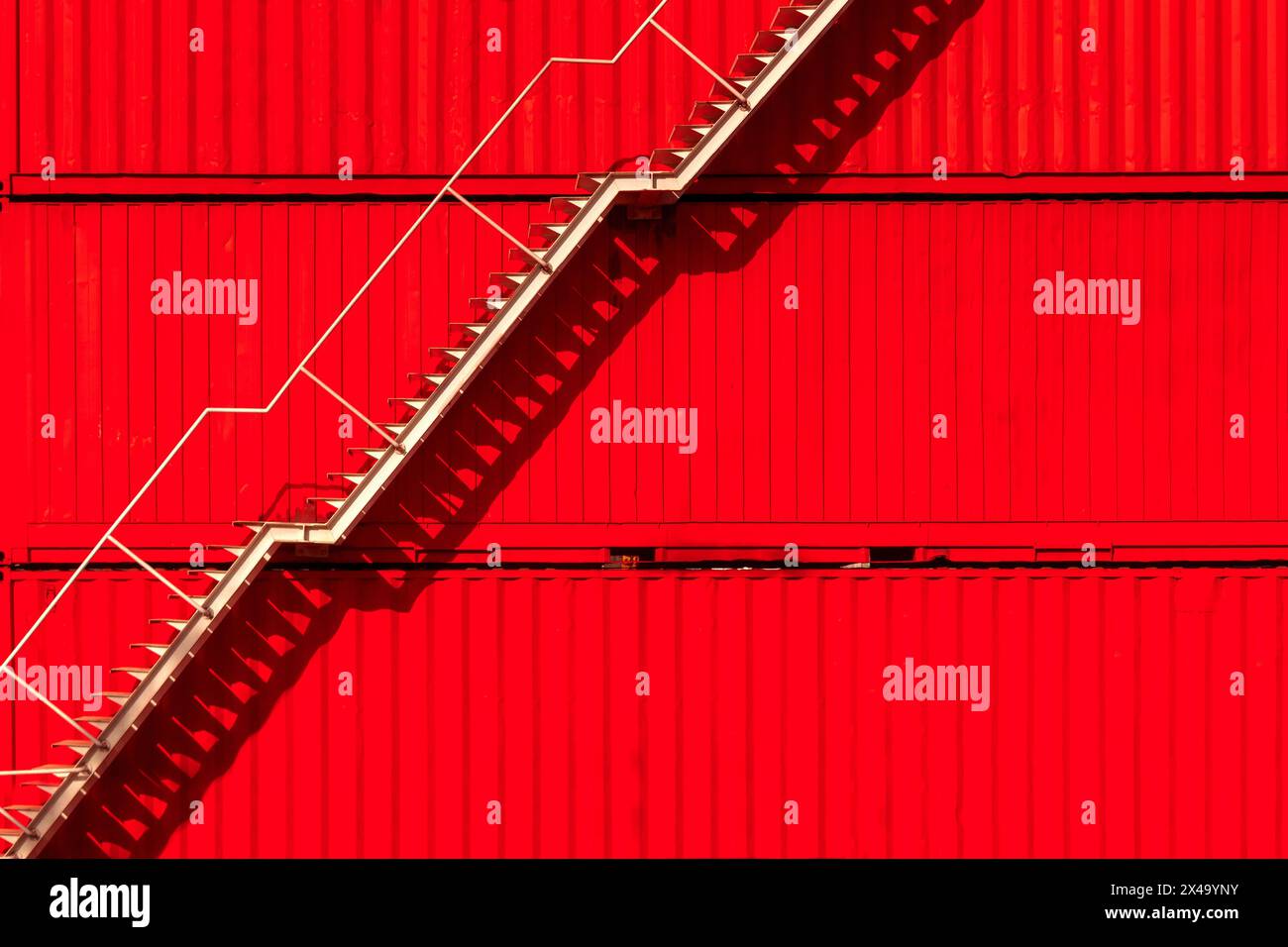 Weiße Stahltreppe auf rotem Containerhintergrund. Industrie Stockfoto