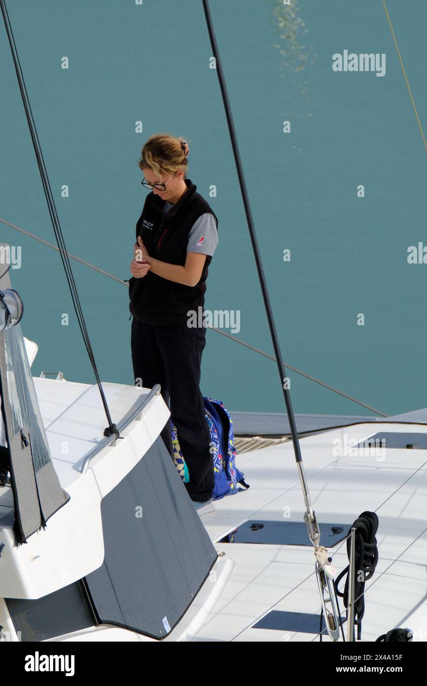 Italien, Sizilien, Mittelmeer, Marina di Ragusa (Provinz Ragusa); 1. Mai 2024, Frau auf einem Katamaran-Segelboot im Hafen - EDITORIAL Stockfoto