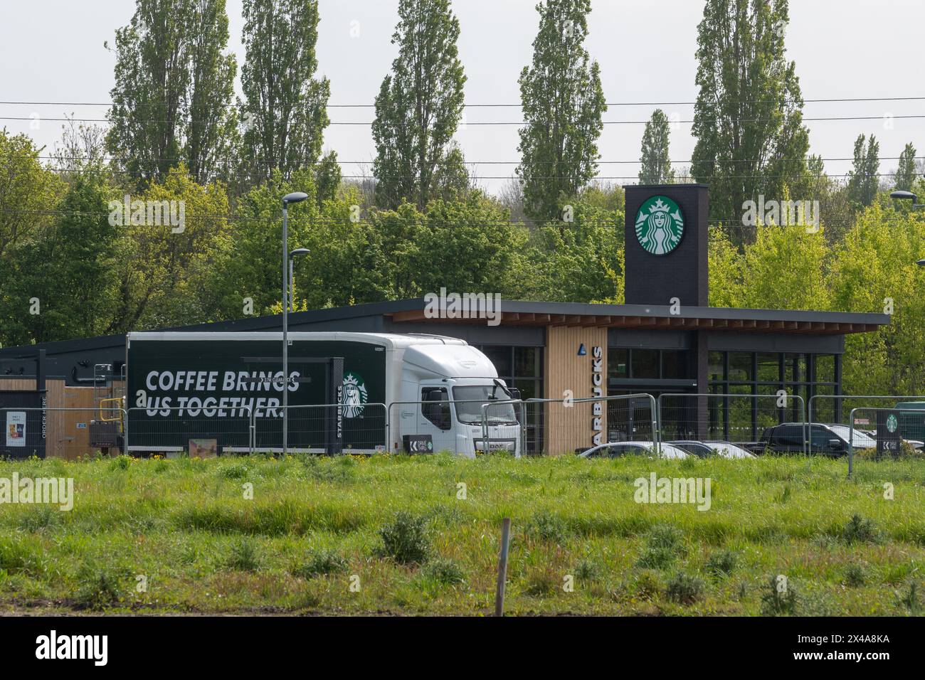 Starbucks Drive-Thru Coffee Shop mit Lieferwagen oder LKW mit Kaffee bringt uns zusammen auf Side, Tongham Services, Surrey, England, Großbritannien Stockfoto