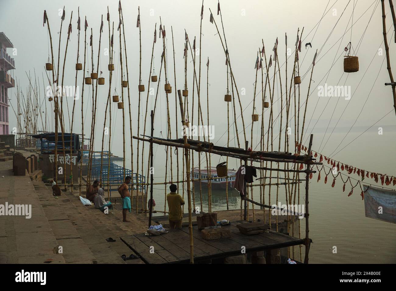 Korbkörbe hängen an langen Bambusstangen am Ufer des Ganges bei Varanasi, Indien. Stockfoto