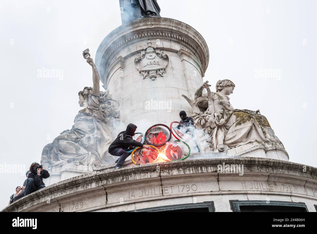 Anti-JO-Aktion auf der Statue de la Republique auf dem Platz der Republik. Feuer auf die JOP-Ringe. Ein Banner, kein Entzug, kein JOP. Scheiß auf die O Limpics. 1. Mai 2024 Demonstration in Paris gegen Sparmaßnahmen, für Arbeitsplätze und Löhne. Frankreich, Patis am 1. Mai 2024. Foto von Patricia Huchot-Boissier / Collectif DyF. Stockfoto