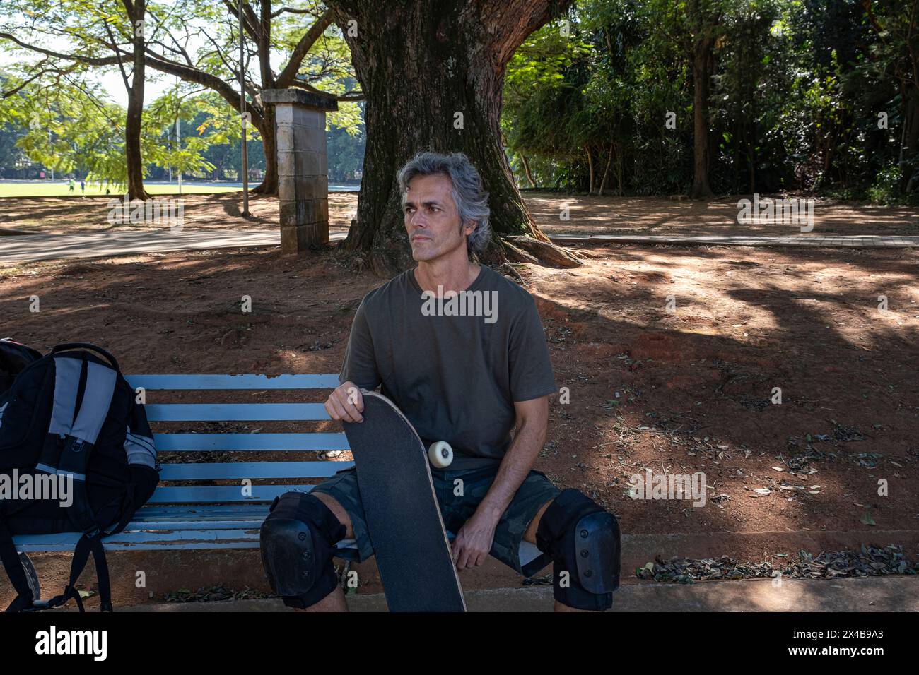 Brasilianischer Skateboarder über 50 Jahre, der sich auf einer Bank in einem Quadrat entspannt 1. Stockfoto