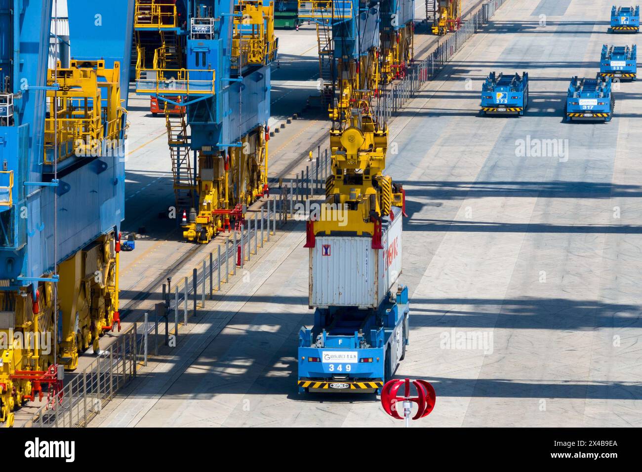 QINGDAO, CHINA - 1. MAI 2024 - im automatisierten Terminal des Hafens Qingdao transportiert ein fahrerloser Tieflader Container vom Terminal in den Behälter Stockfoto QINGDAO, CHINA - 1. MAI 2024 - im automatisierten Terminal des Hafens Qingdao transportiert ein fahrerloser Tieflader Container vom Terminal in den Behälter Stockfoto