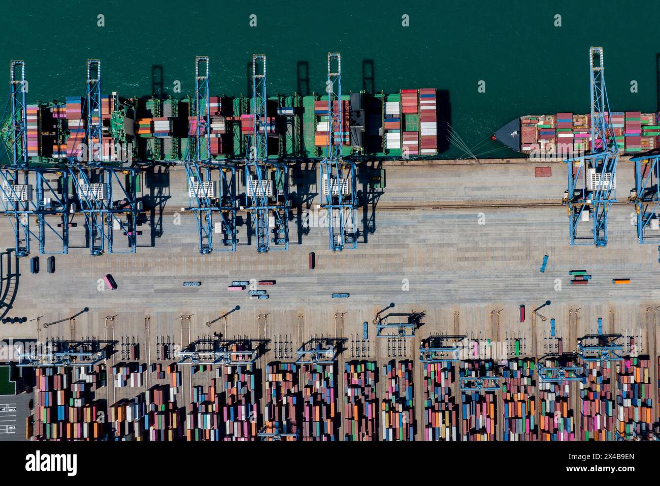 QINGDAO, CHINA - 1. MAI 2024 - im automatisierten Terminal des Hafens Qingdao transportiert ein fahrerloser Tieflader Container vom Terminal in den Behälter Stockfoto QINGDAO, CHINA - 1. MAI 2024 - im automatisierten Terminal des Hafens Qingdao transportiert ein fahrerloser Tieflader Container vom Terminal in den Behälter Stockfoto