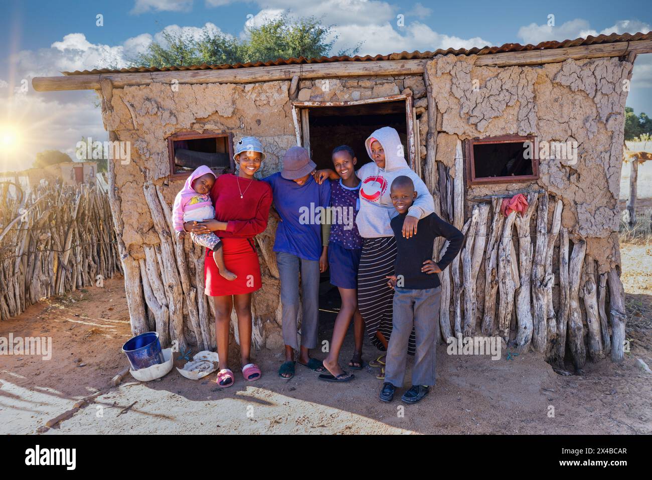 afrikanisches Dorf, große Großfamilie, die vor dem Lehmhaus im Dorf steht Stockfoto