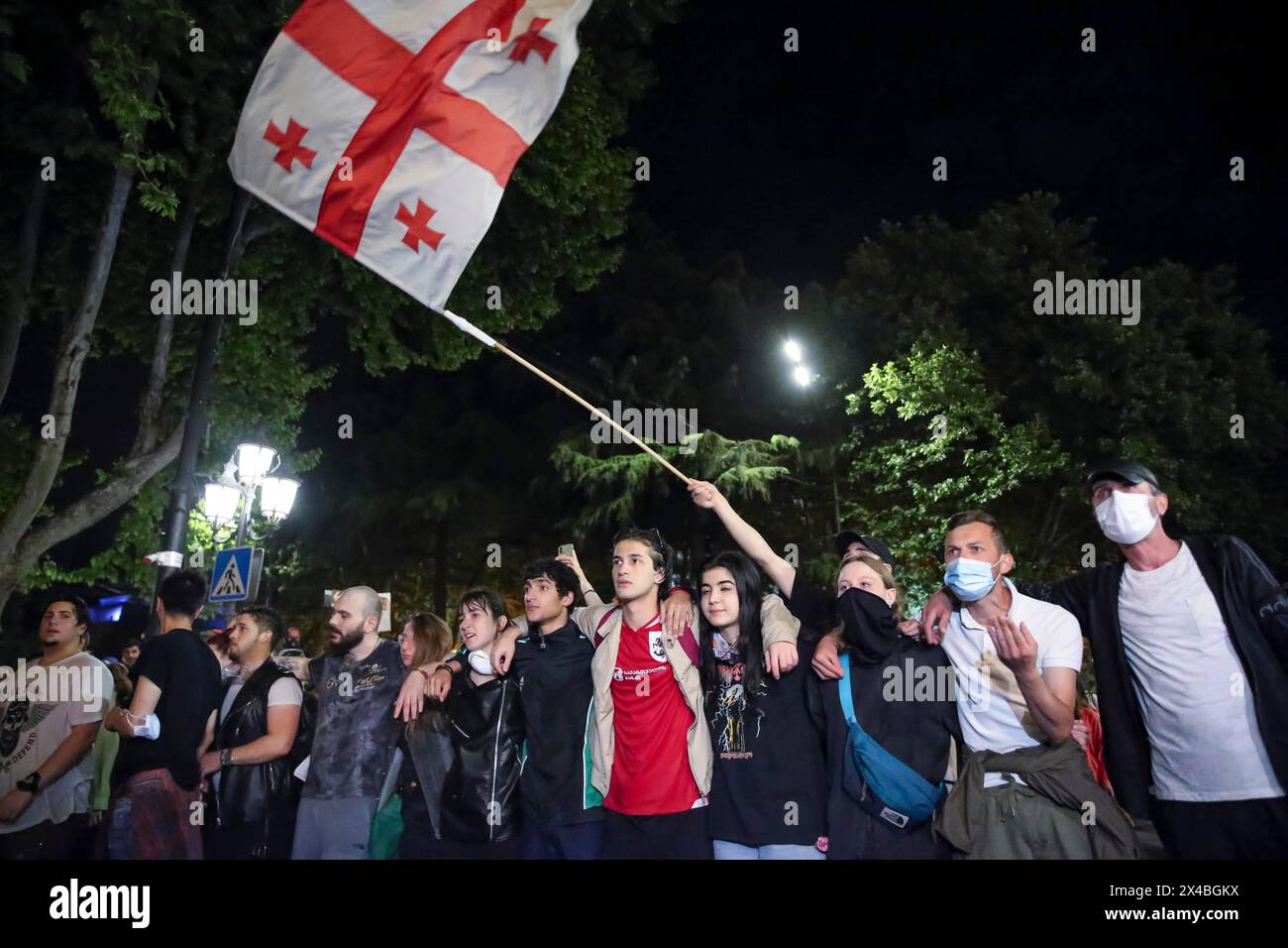 Demonstrators wave a Georgian national flag standing in front of police block during an opposition protest against a bill near the Parliament building in Tbilisi, Georgia, on Thursday, May 2, 2024. Protesters denounce the bill as "the Russian law" because Moscow uses similar legislation to stigmatize independent news media and organizations critical of the Kremlin. (AP Photo/Zurab Tsertsvadze) Stockfoto