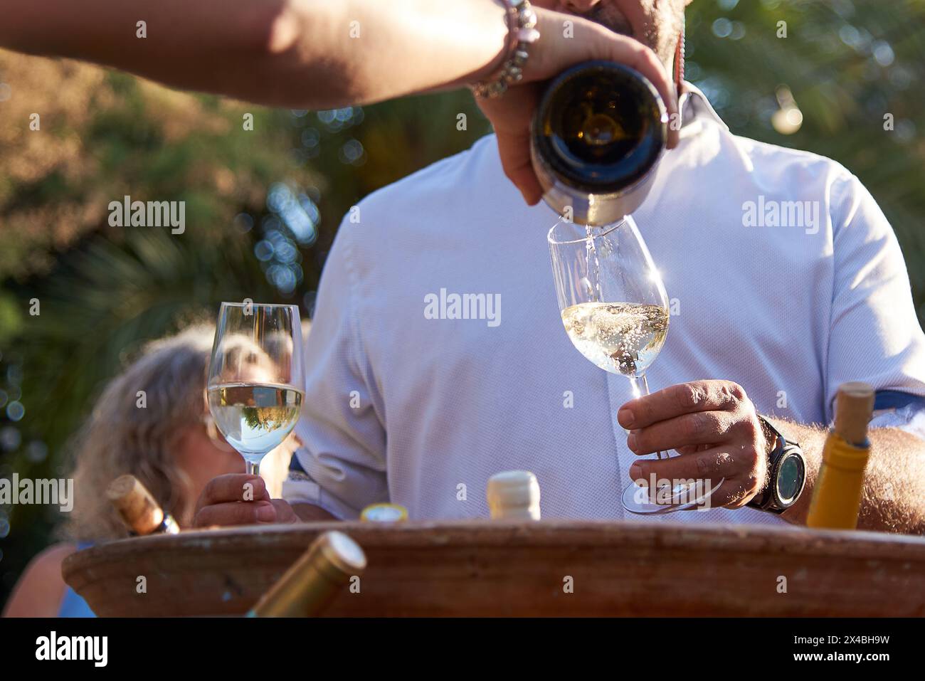 Eine Person serviert Weißwein im Glas bei einer Veranstaltung im Freien. Perfekt für einen Moment der Entspannung Stockfoto