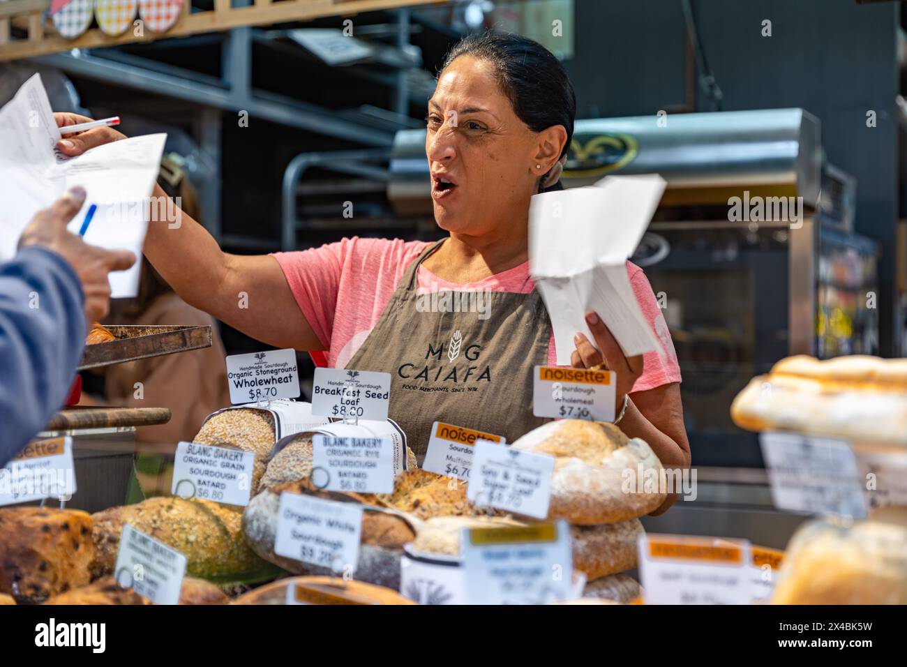 MELBOURNE, AUSTRALIEN - 12. APRIL 2024: Weibliche Verkäuferin auf dem Queen Victoria Market Stockfoto