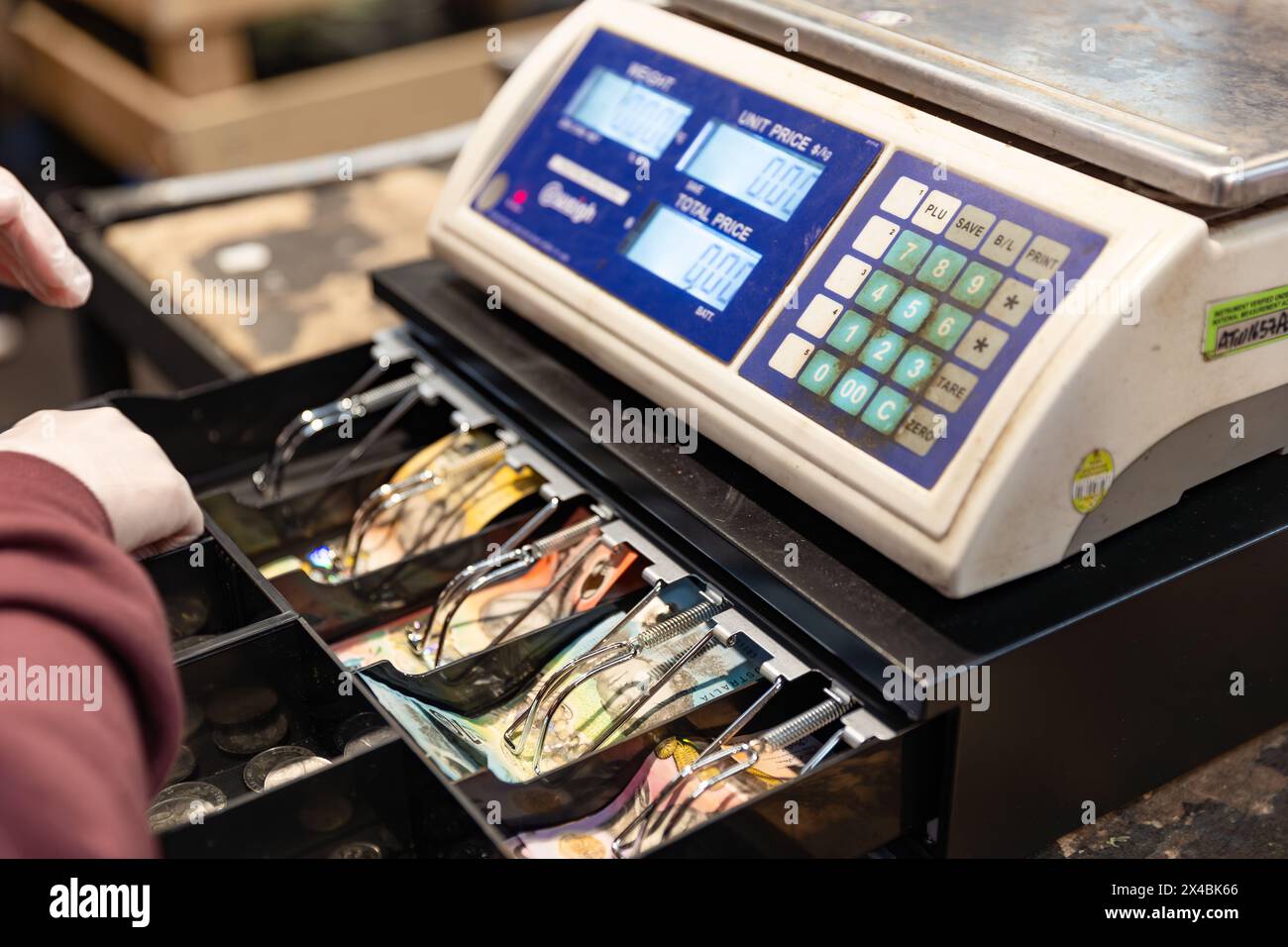 Eine krumme Kasse auf einem Bauernmarkt mit gestapelten Banknoten darin Stockfoto