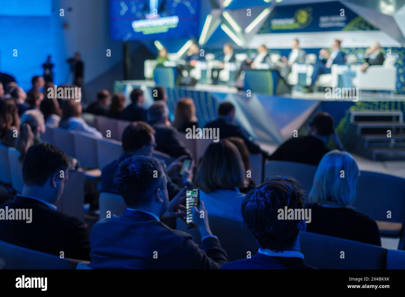 Eine Gruppe von Unternehmensleitern nahm an einer Diskussion auf einer großen, modernen internationalen Konferenz Teil. Die Teilnehmer hören aufmerksam zu und machen sich Notizen. Stockfoto