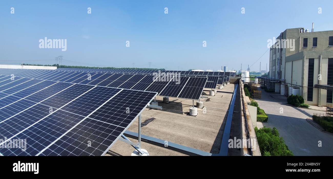 Solar Panel Array auf einem Dach eines Industriebaus unter klarem blauem Himmel /Dongying China Stockfoto