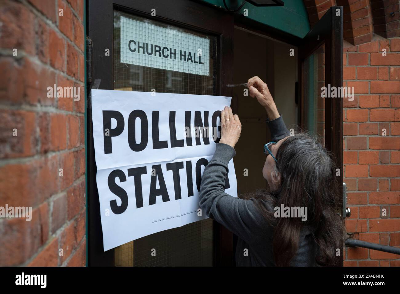 Ein Mitarbeiter bringt Plakate vor der Wahlstation der Baptist Church in East Dulwich an dem Tag, an dem die Londoner am 2. Mai 2024 in London für ihren Bürgermeister und die Mitglieder der Londoner Versammlung stimmen. Stockfoto