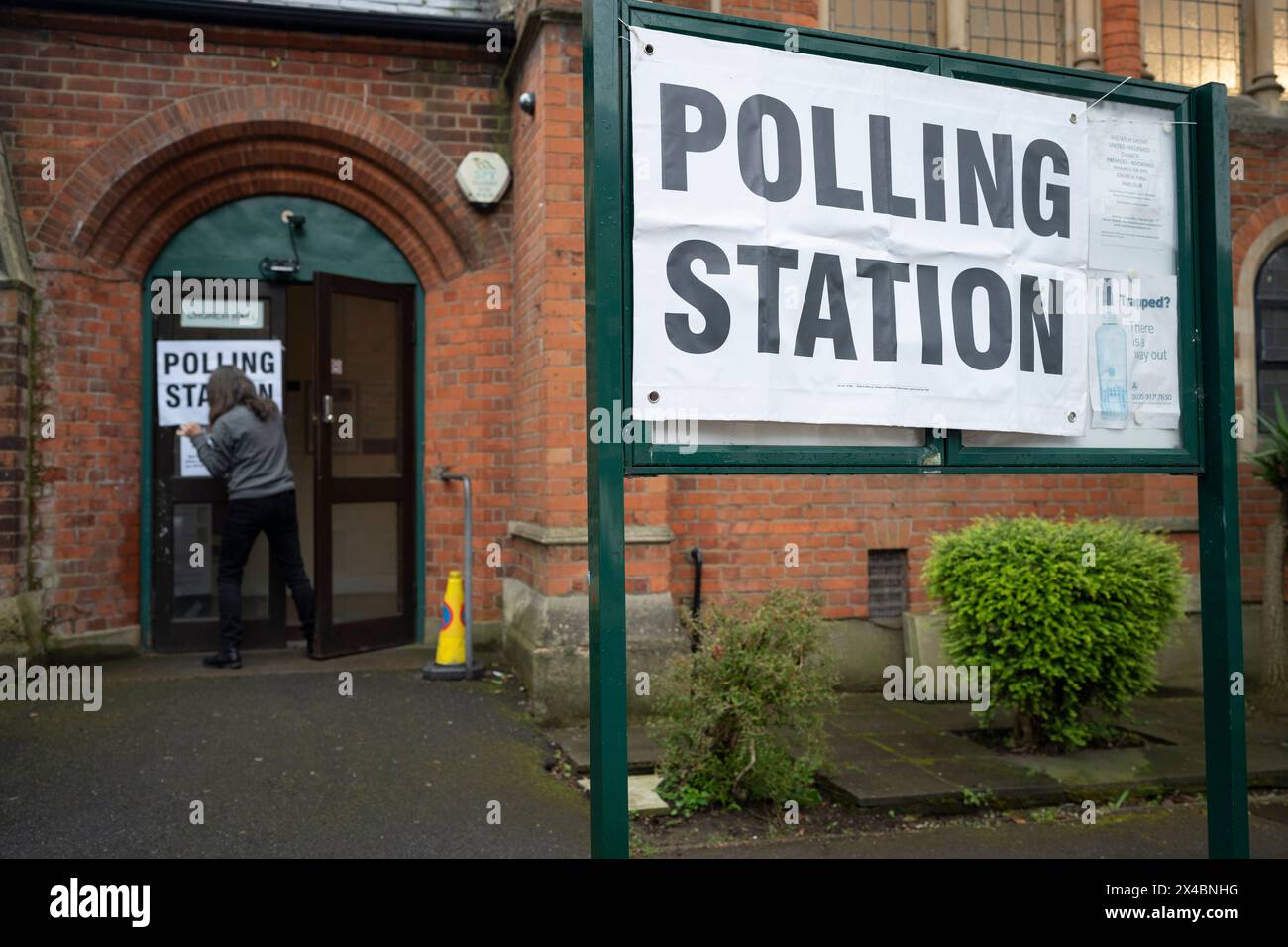 Ein Mitarbeiter bringt Plakate vor der Wahlstation der Baptist Church in East Dulwich an dem Tag, an dem die Londoner am 2. Mai 2024 in London für ihren Bürgermeister und die Mitglieder der Londoner Versammlung stimmen. Stockfoto